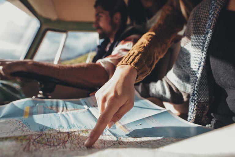 Friends on road trip using map for directions %name Entenda a importância de viajar com filhos
