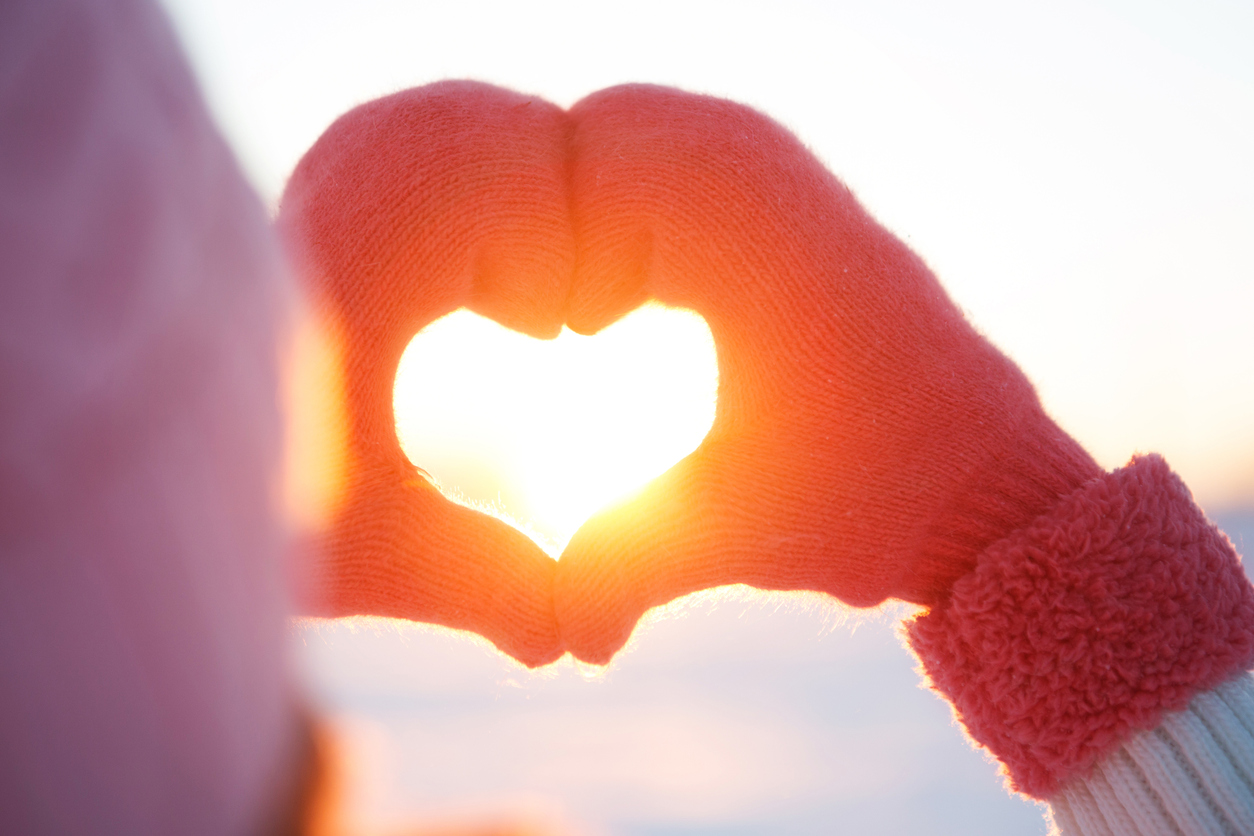 Woman hands in winter gloves Heart symbol